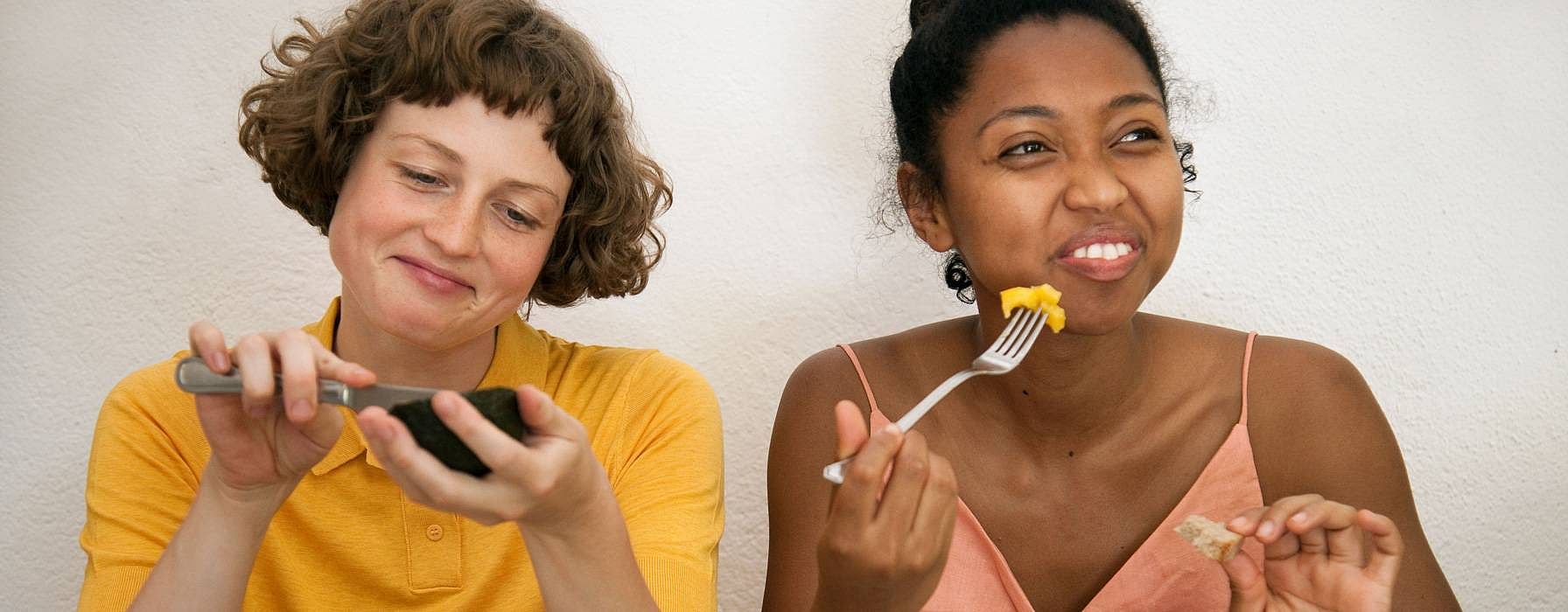 Two women sitting next to eachother and eating.