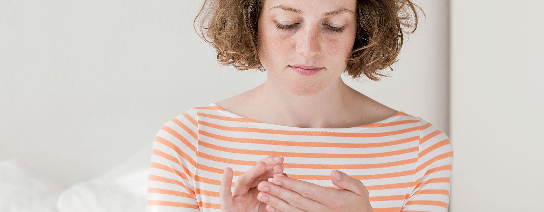 woman is gently applying a weleda product to her hands