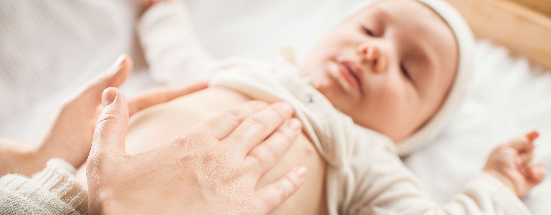 Baby lying down with parents hands on belly