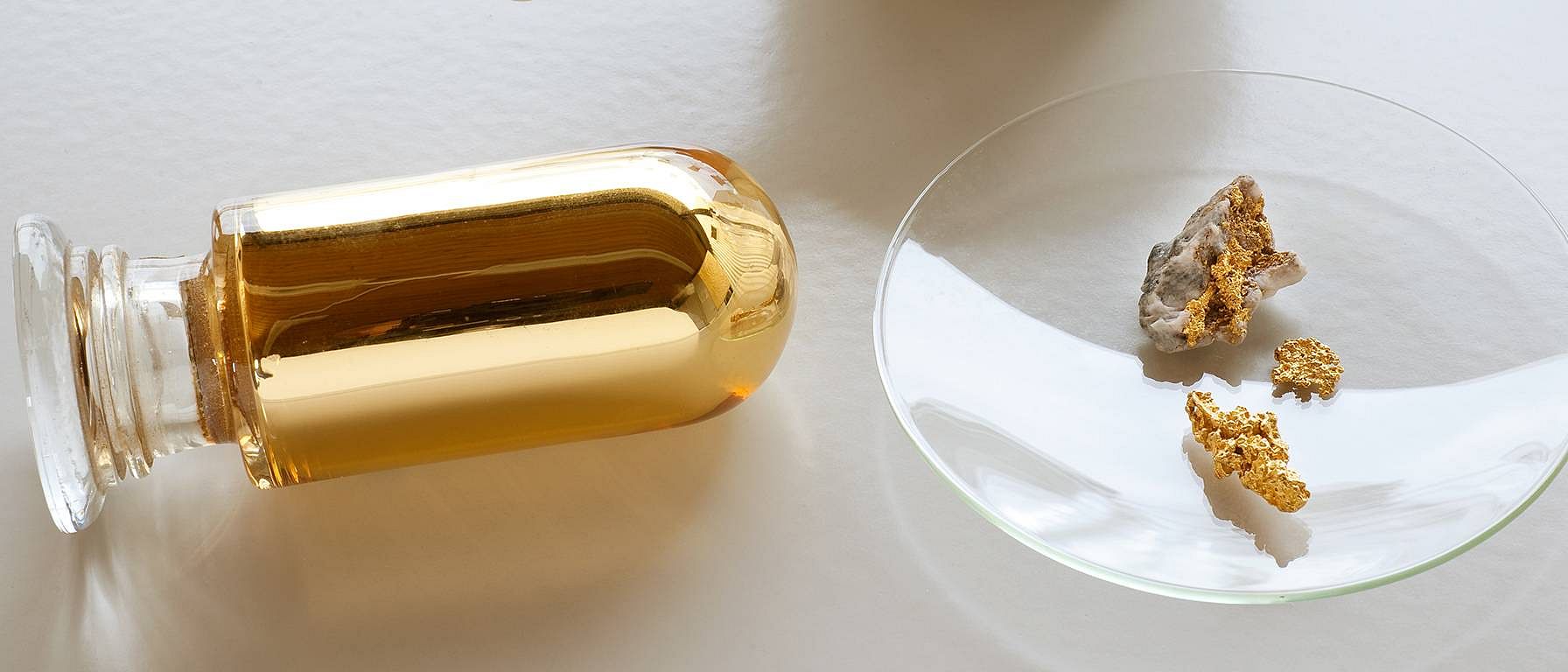 Glass vile with gold and gold nuggets on petri dish.