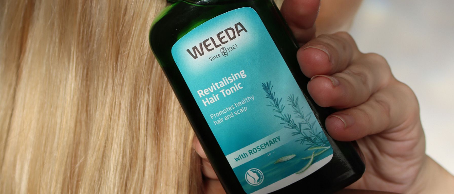 woman holding hair tonic in hand with hair