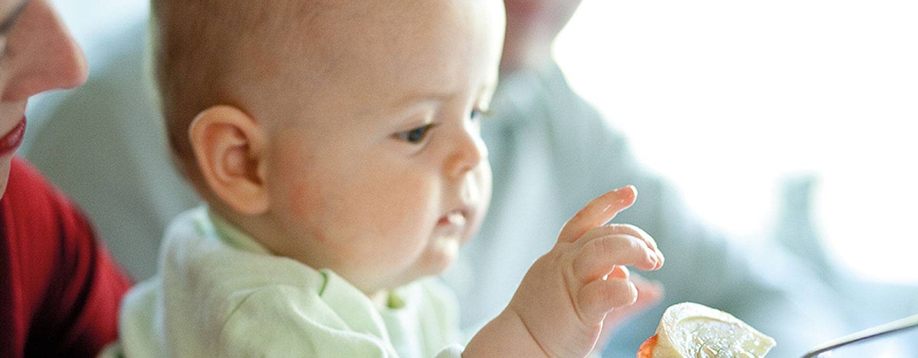 Baby looking at food on a spoon.