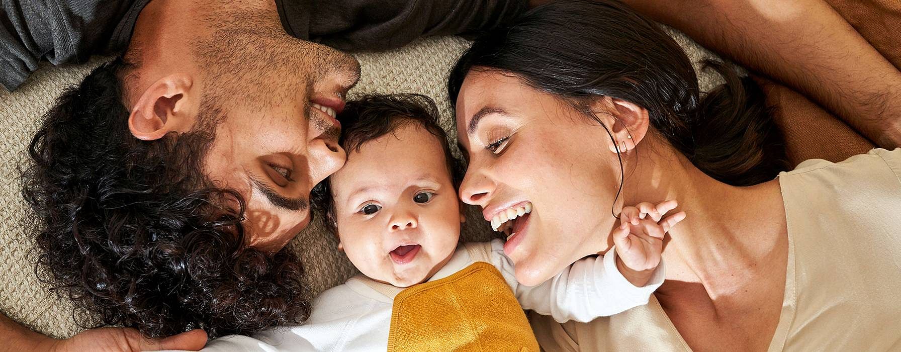 Parents lying down around baby