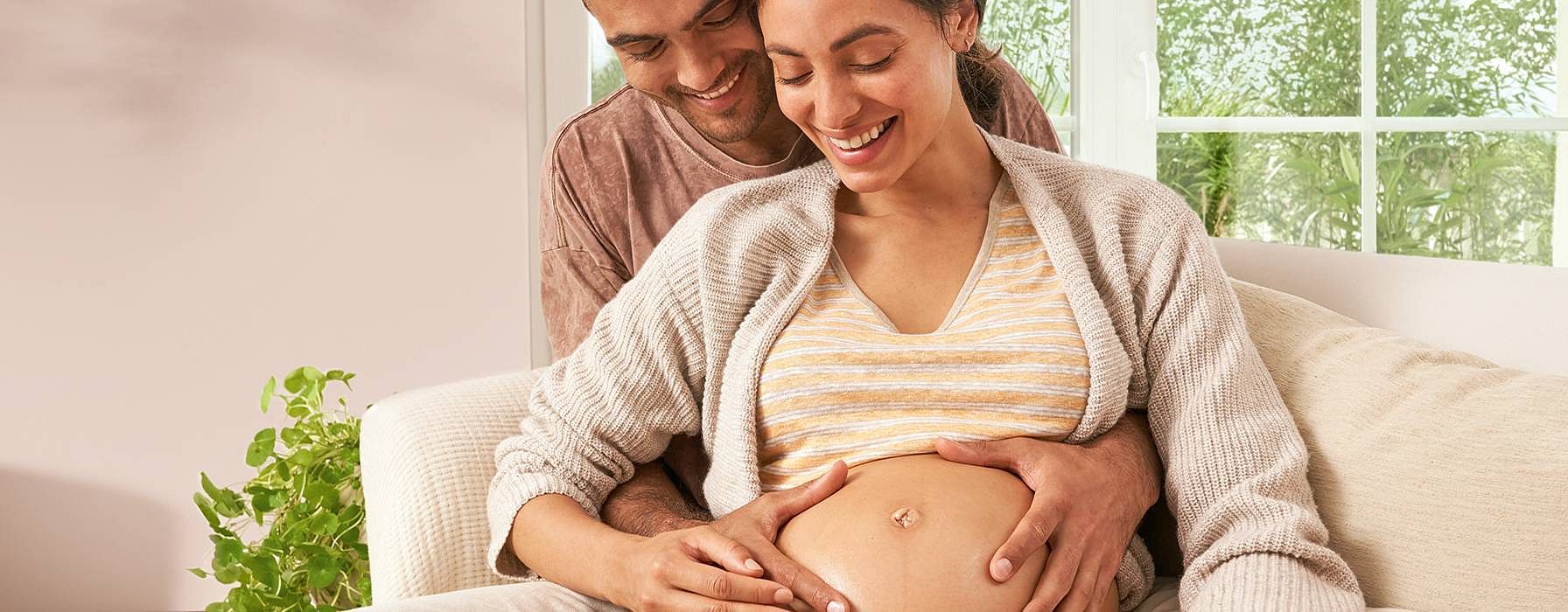 Pregnant woman and partner embracing.