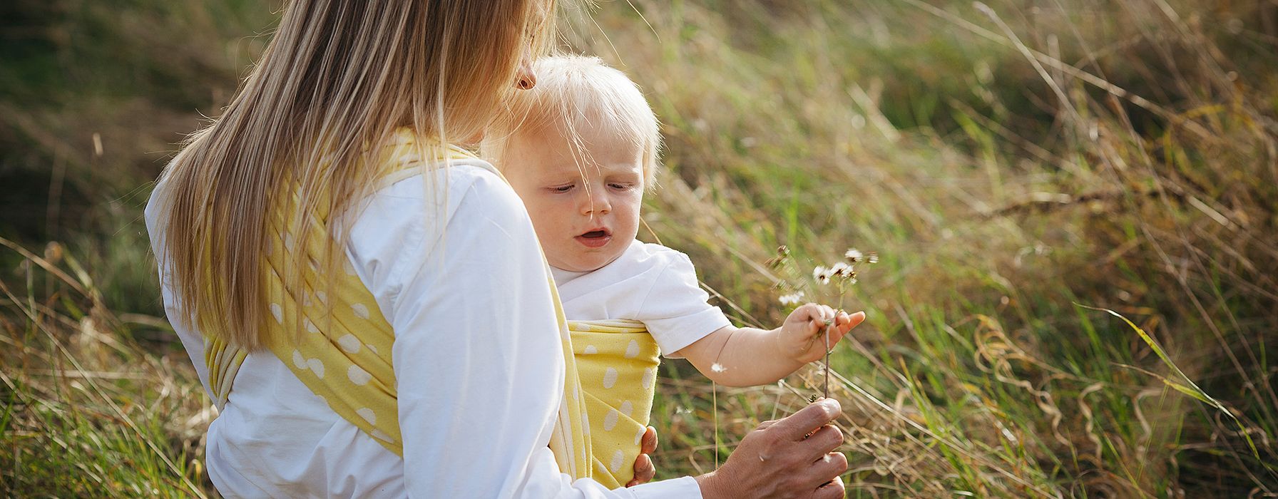 Woman carrying baby outside.