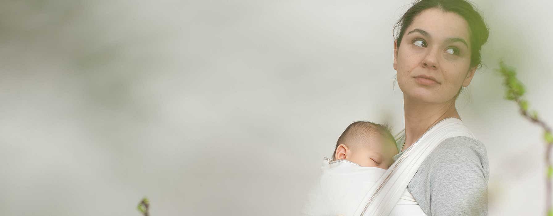 Mother carrying baby leaning on a wall