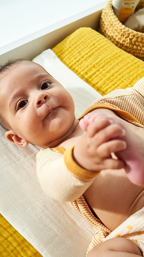 Baby on change table smiling dressed in yellow