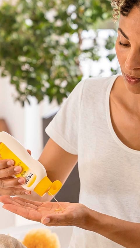Mother putting calendula baby oil onto her hand