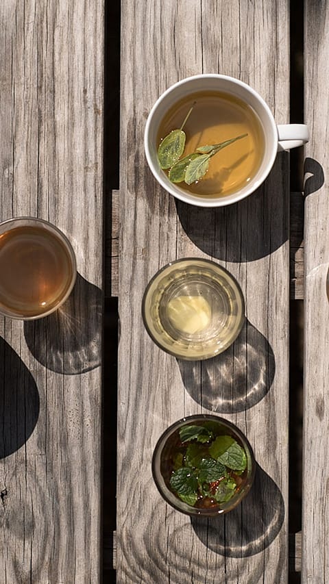 Cups with tea and glasses of water on wooden floorboards.