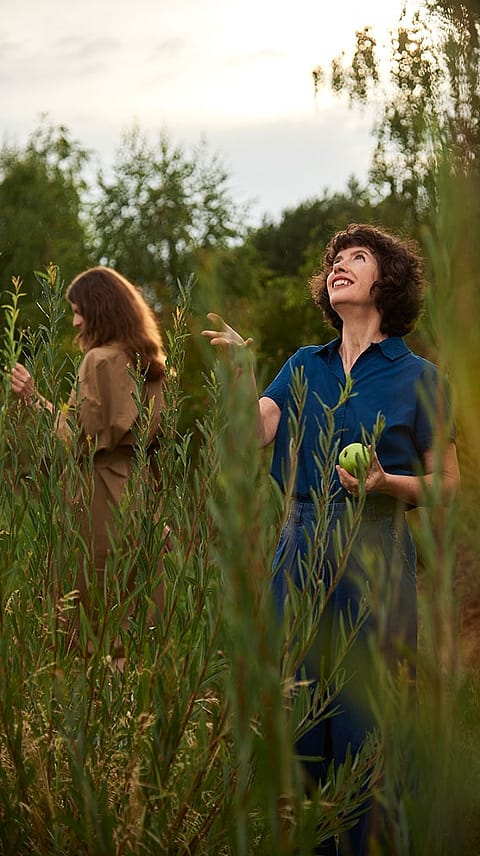 Woman eating an apple in a field.