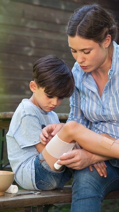 Woman bandaging child's leg.