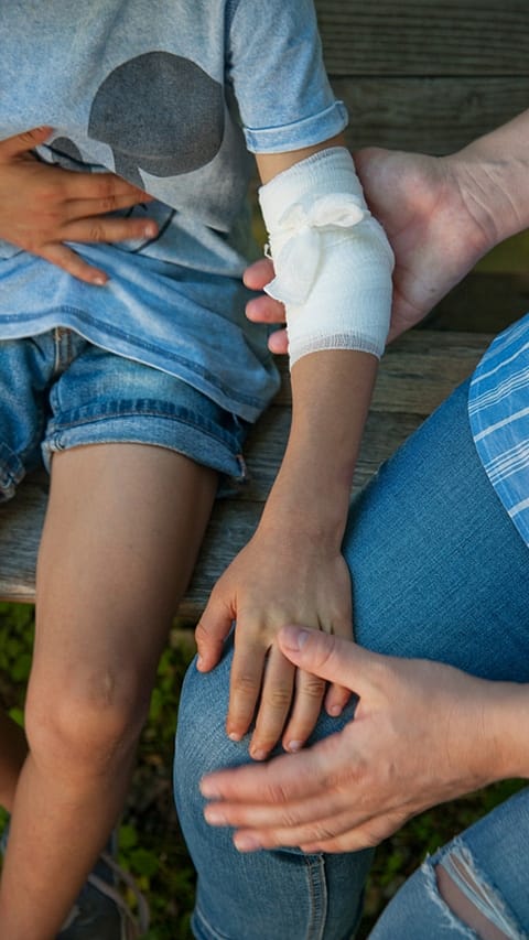 Woman holding a childs arm that has been bandaged.
