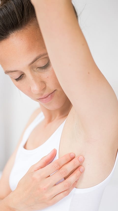 Woman with arm reaised looking at her arm pit.