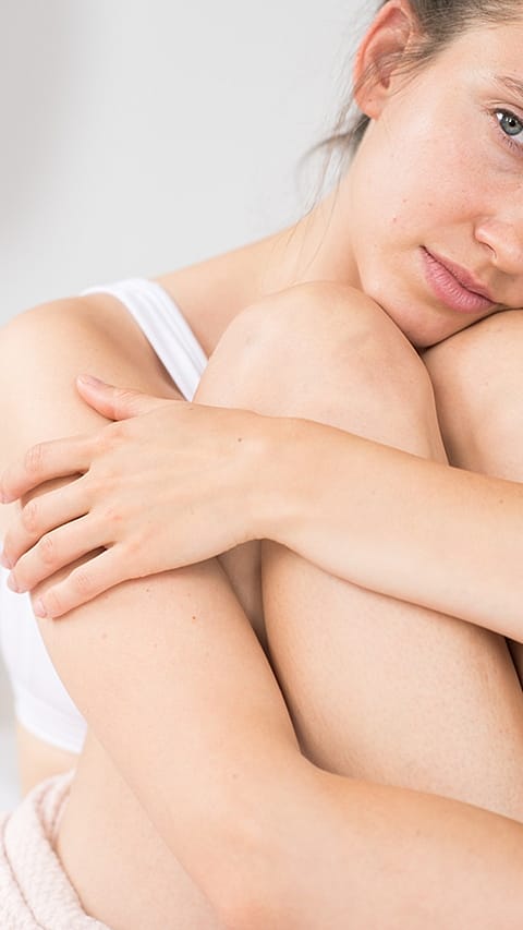 Woman hugging her legs.