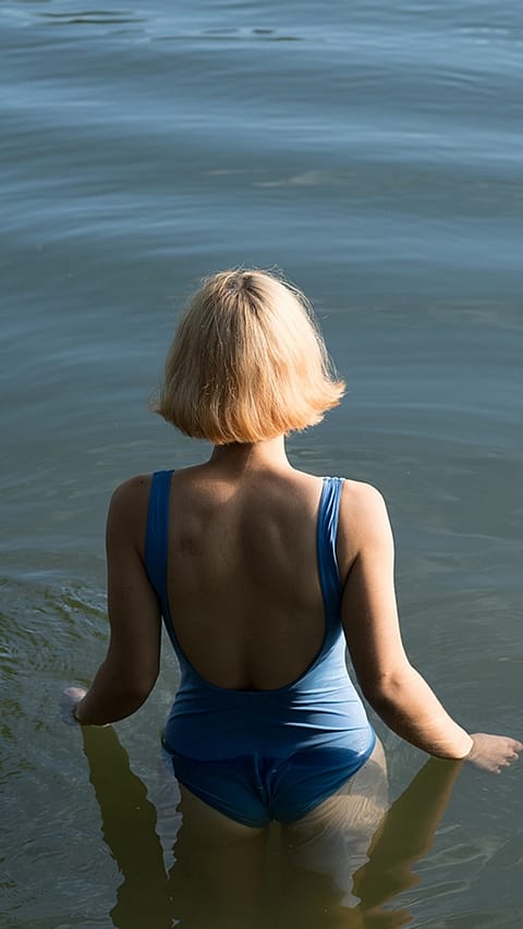 Woman's back entering lake.