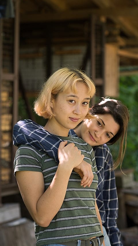 Two women embracing and looking at camera.