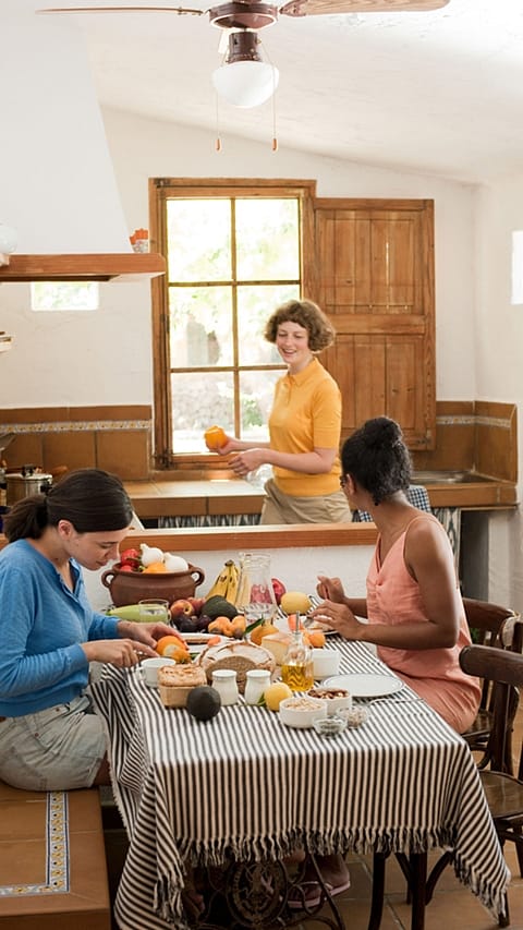 Three women preparing healthy food in a kitchen.