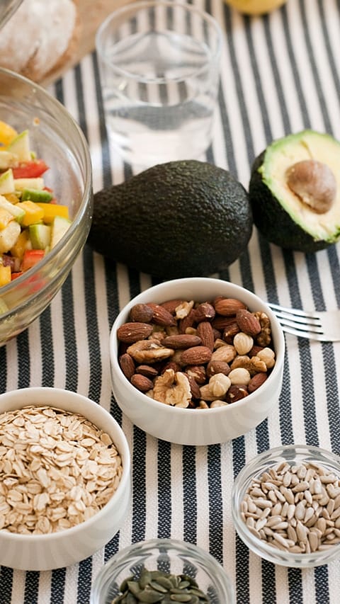 Almonds, avocado, oats and avocados layed on a table.