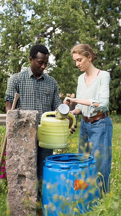 Man and woman gahering water from a bucket.
