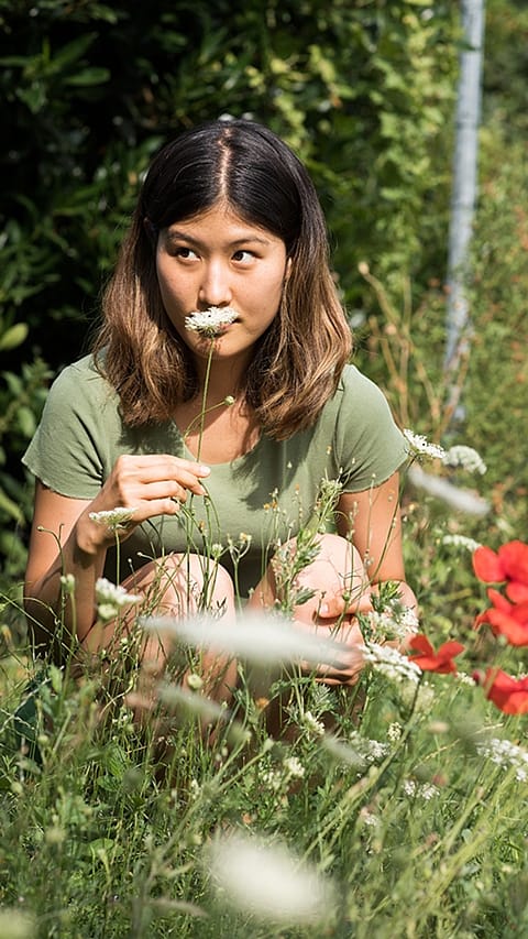 Girl in a field looking at plants.