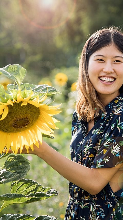 Girl smiling in a field of sunflowers.