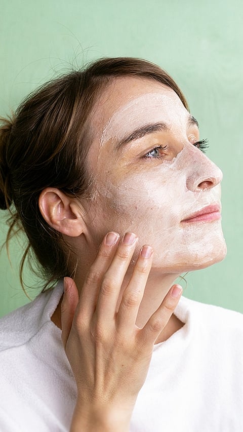 woman applying facial cream mask