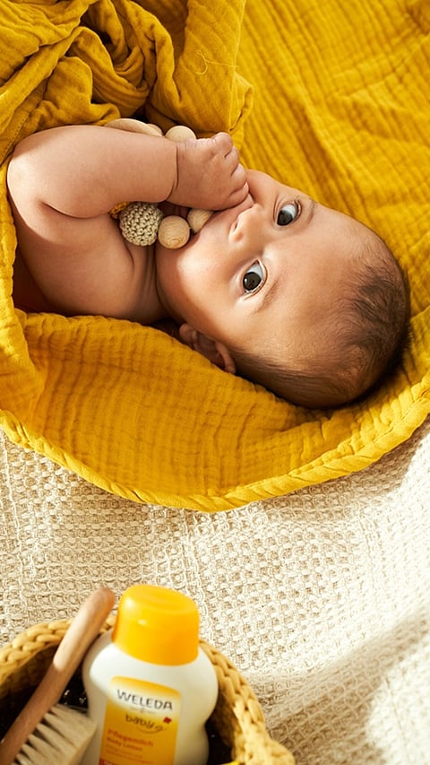 Baby in yellow wrap sucking his thumb