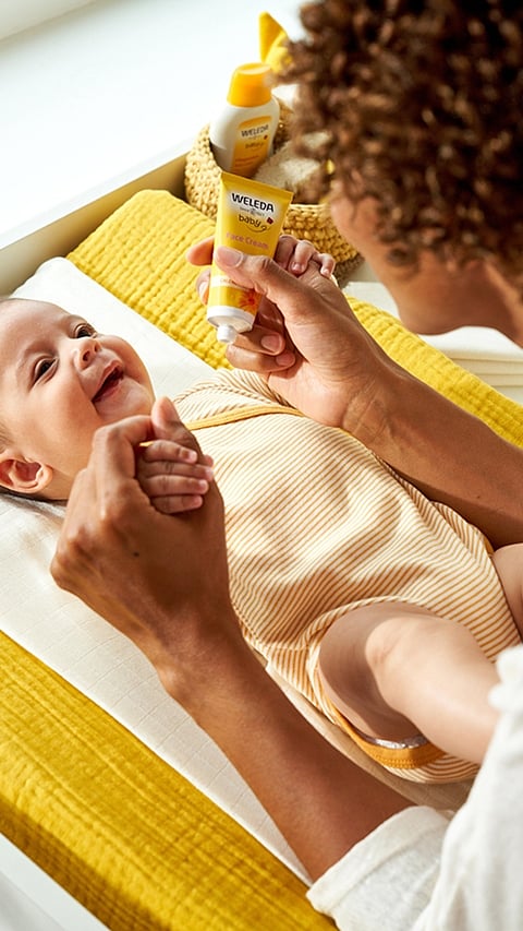 Mother caring for baby on yellow change table