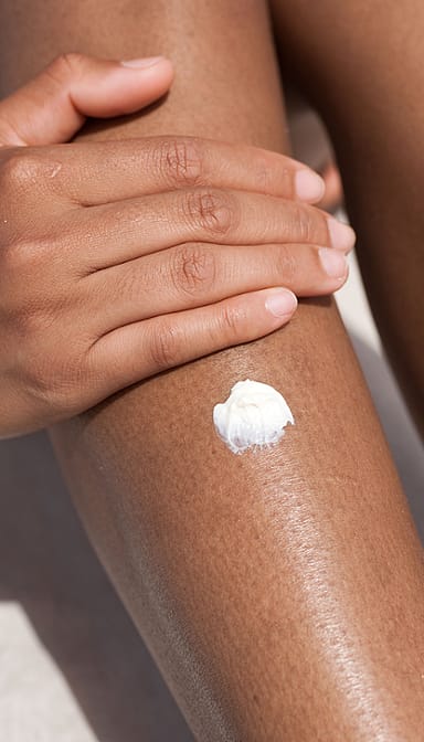 Dark skin woman's leg with a spot of moisturiser.