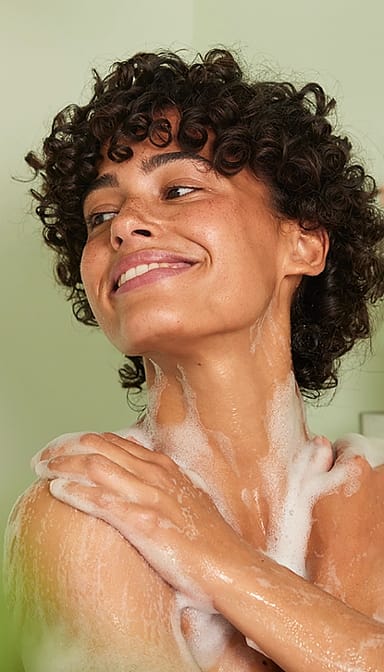 woman smiling and applying body wash cropped.