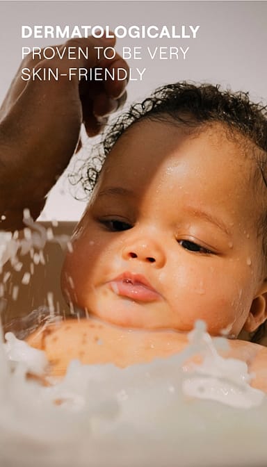 baby bathing in tub with water sprinkles and text.
