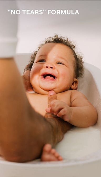 baby bathing and smiling, hold in hands with text.