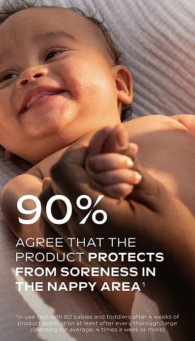 Dark skin baby lying down smiling with hands being held and Calendula nappy change cream fragrance free text