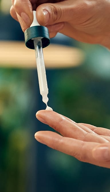 Firming face serum pipette being squeezed onto a finger before application.