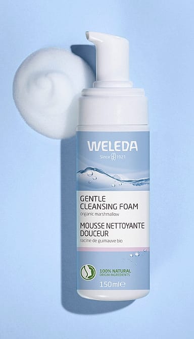 Open Gentle Cleansing Foam bottle on a light blue background with foam texture next to it.