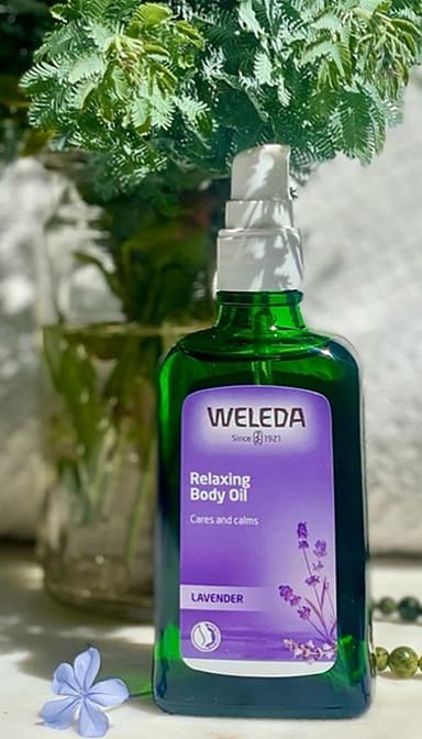 Relaxing Body Oil Lavender infront of a fern in a vase.