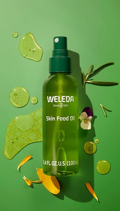 Skin Food Ultra-Light Dry Oil bottle and oil texture surrounded by yellow petals on a green background.