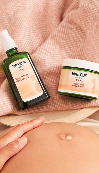 stretch mark massage oil and body butter next to baby belly