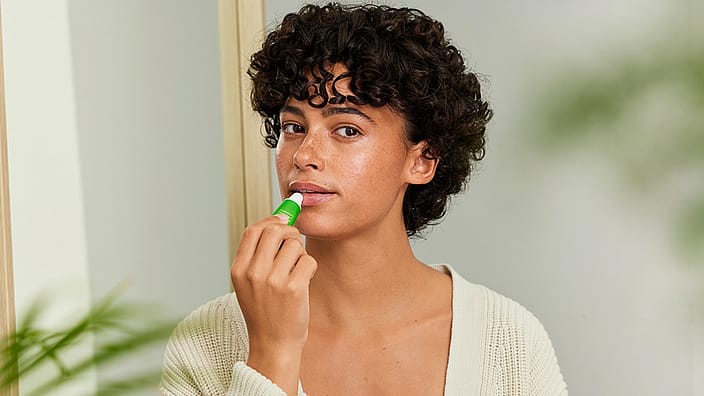 Woman putting Skin Food lip balm on lips