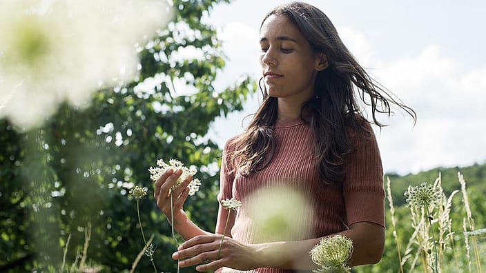 Girl in field holding flowers.