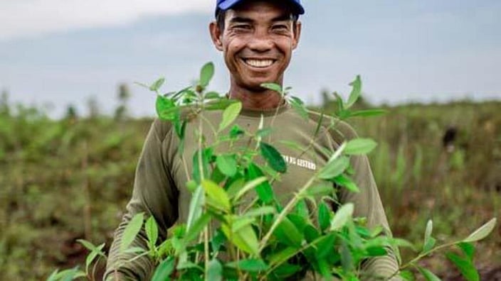 Smiling man in a field holding a crop