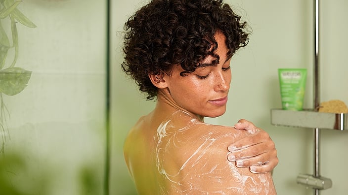 Girl in shower exfoliating with Birch Body Scrub