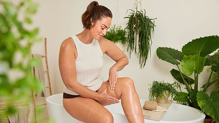 Girl massaging her legs with weleda body oil
