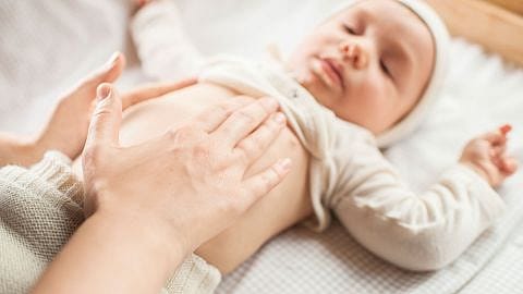Baby lying down with parents hands on belly