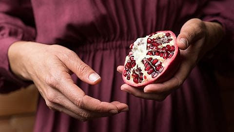 woman holding pomegranate in hand