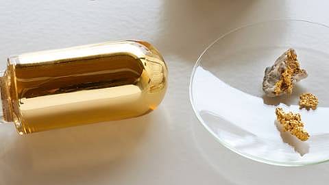 Glass vile with gold and gold nuggets on petri dish.