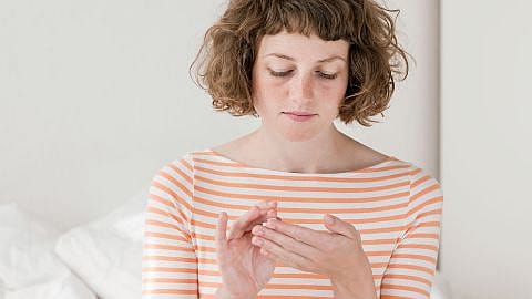 woman is gently applying a weleda product to her hands