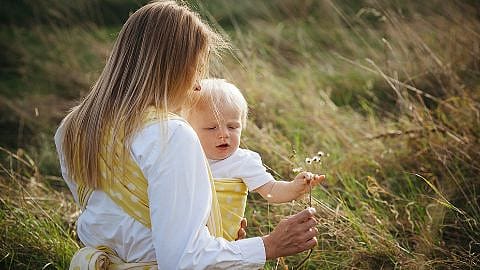 Woman carrying baby outside.