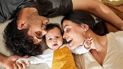 Parents lying down around baby