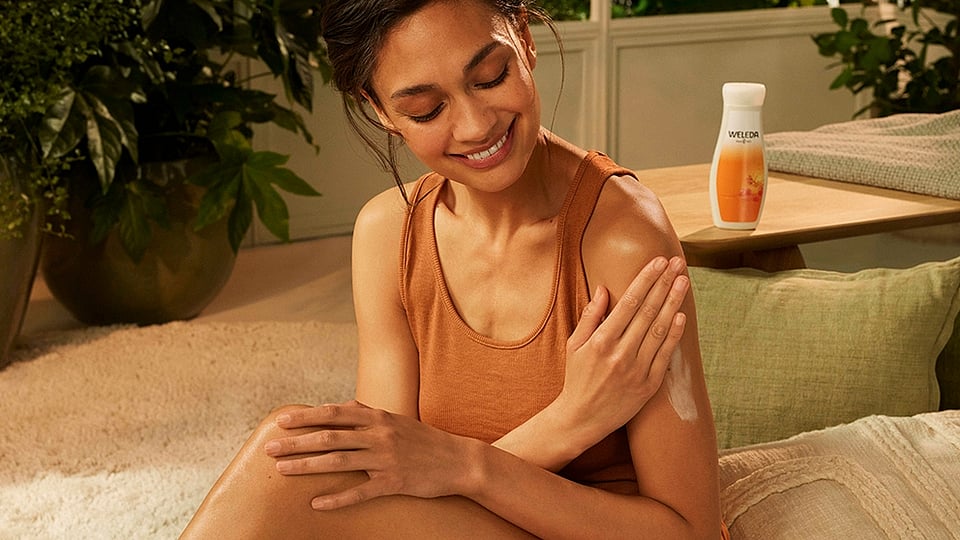 Woman applying body lotion to her arm.